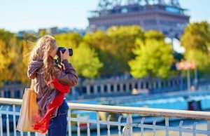 Best Photo Spots in Paris (Map & Timing Tips) Woman photographer on a Paris bridge with the Eiffel Tower in the background