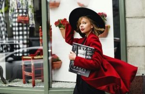 Paris in Spring: Best Time & What to Wear Woman in a red coat and black hat walking past a Paris boutique — stylish spring outfit
