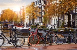 Amsterdam 2-Day Itinerary: The Perfect First-Timer Route Bicycles along an Amsterdam canal at sunrise with historic Dutch houses in the background