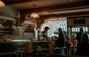 Best Cafés in Amsterdam: Cozy Spots for Coffee, Work & People-Watching Cozy Amsterdam café interior with people ordering coffee and warm wooden details