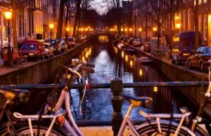 Amsterdam Hidden Gems: Secret Spots & Unseen Things to Do Evening canal view in Amsterdam with warm street lights and bicycles on a bridge