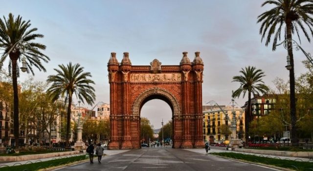 Arc de Triomf framed by palm trees at golden hour in Barcelona, Spain