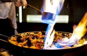 Best Paella in Barcelona: Where to Eat by the Sea (Map) Seafood paella being flambéed in a pan in Barcelona