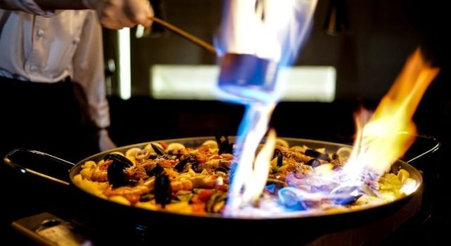 Seafood paella being flambéed in a pan in Barcelona