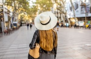 Barcelona in Spring: Best Time & What to Wear Woman in a wide-brim hat and light jacket walking along La Rambla, Barcelona in spring.