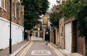 London Neighborhoods Guide: The Best Areas to Explore on Your Trip Narrow residential street in London with brick houses and people walking, showcasing the city's quiet local neighborhoods