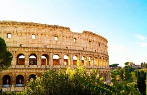 Monti & Celio Guide: Vintage Shops, Wine Bars & Colosseum Views Side view of the Colosseum framed by greenery from the Celio hill in Rome