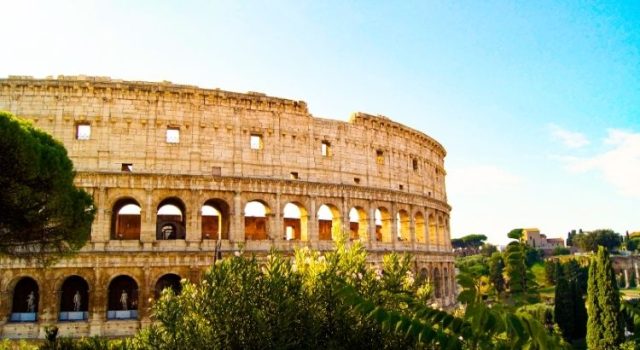 Side view of the Colosseum framed by greenery from the Celio hill in Rome