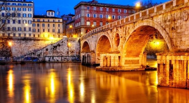 Ponte Sisto at blue hour with warm lights reflecting on the Tiber in Rome