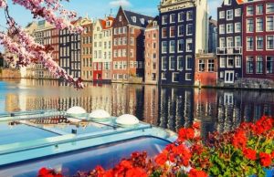 Amsterdam in Spring: Tulips, Keukenhof & Canal Bloom Season Amsterdam canals and historic canal houses decorated with spring cherry blossoms and colorful flowers by the water.