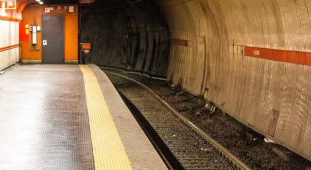 Empty Rome metro platform showing curved tunnel and yellow safety line near the tracks