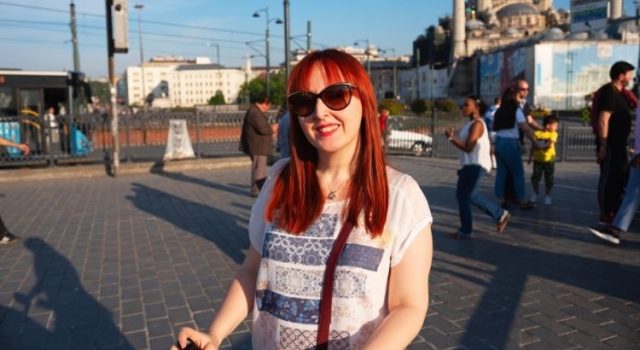 Woman enjoying Istanbul street food near Galata Bridge, famous for balık ekmek (fish sandwich) vendors and Bosphorus views