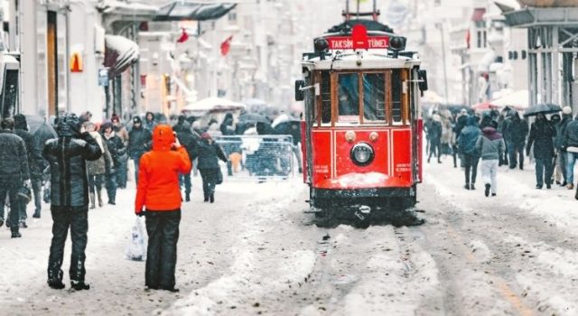 istiklal-street-red-tram-snow-istanbul-winter-2026 Historic red tram on Istiklal Street during snowfall in Istanbul with pedestrians and winter atmosphere